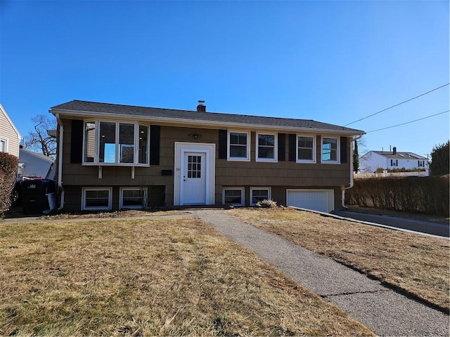 bi-level home with a garage and a front lawn