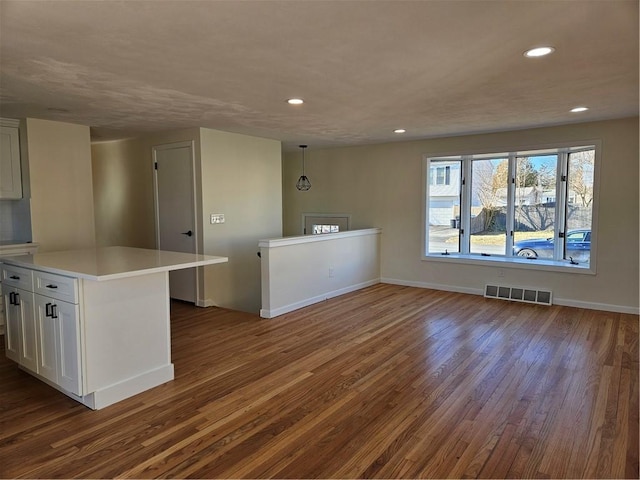 kitchen with white cabinets, hanging light fixtures, and dark hardwood / wood-style flooring