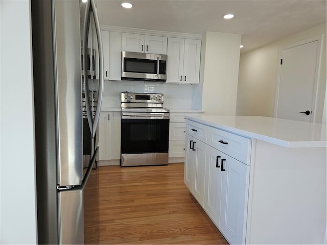 kitchen featuring stainless steel appliances, white cabinets, light wood-type flooring, and backsplash