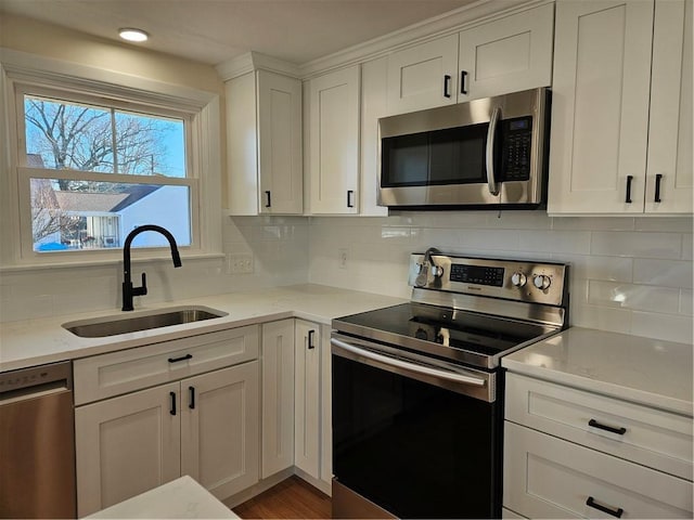 kitchen featuring appliances with stainless steel finishes, light stone counters, decorative backsplash, sink, and white cabinetry