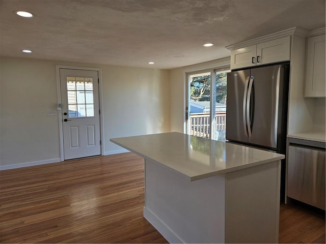 kitchen with a healthy amount of sunlight, stainless steel appliances, white cabinetry, and a center island