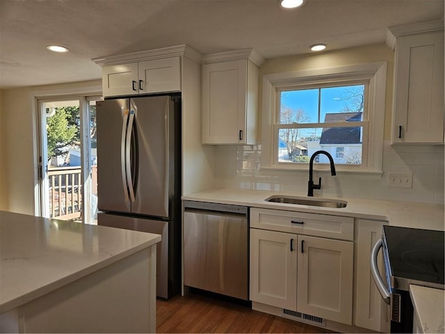 kitchen with stainless steel appliances, white cabinets, decorative backsplash, and sink