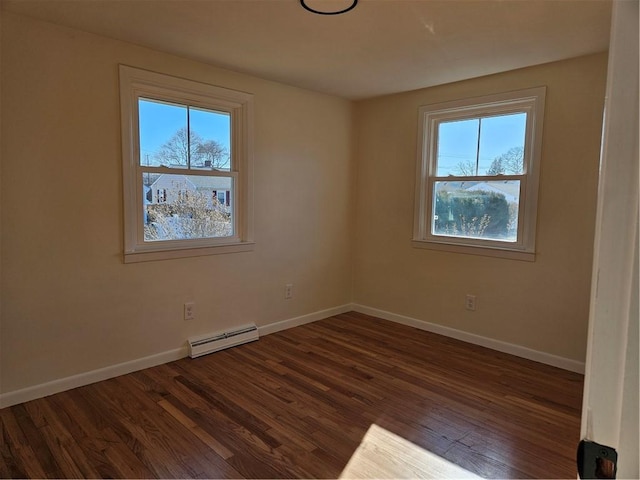 empty room featuring a healthy amount of sunlight, baseboard heating, and dark hardwood / wood-style floors