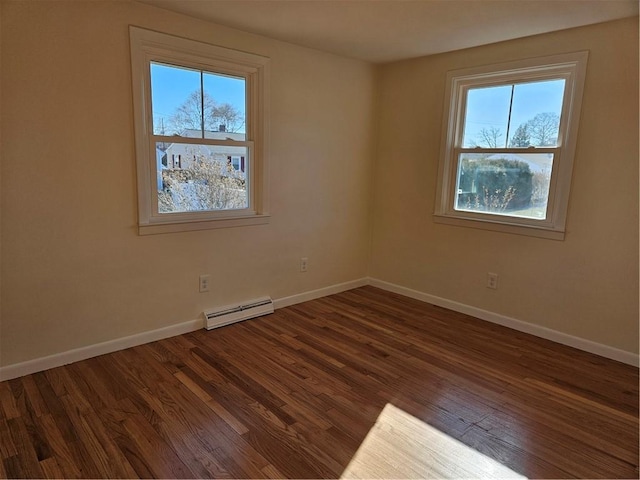 spare room with baseboard heating and dark hardwood / wood-style flooring