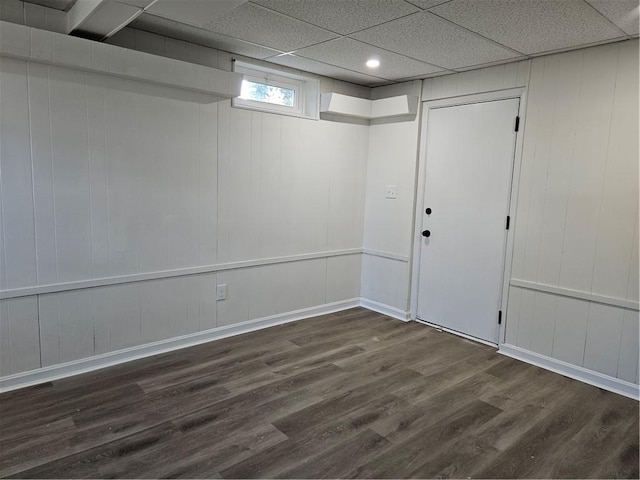 basement featuring a paneled ceiling and dark wood-type flooring