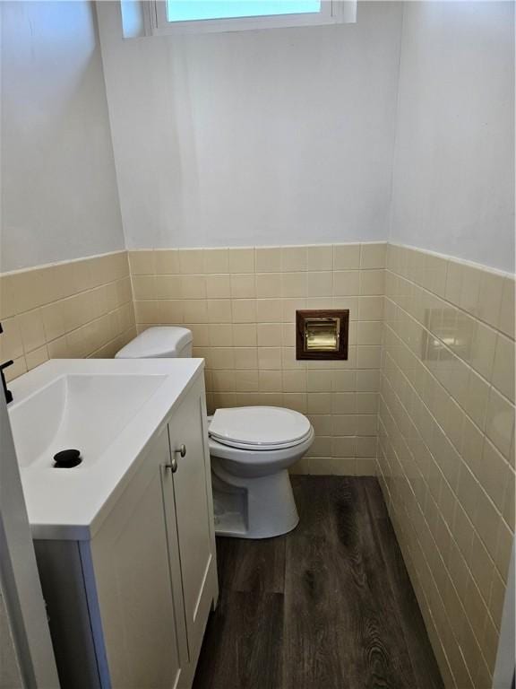 bathroom with tile walls, toilet, vanity, and wood-type flooring