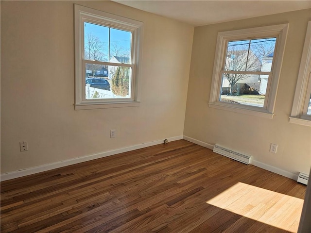 unfurnished room featuring a baseboard heating unit, a healthy amount of sunlight, and dark hardwood / wood-style floors