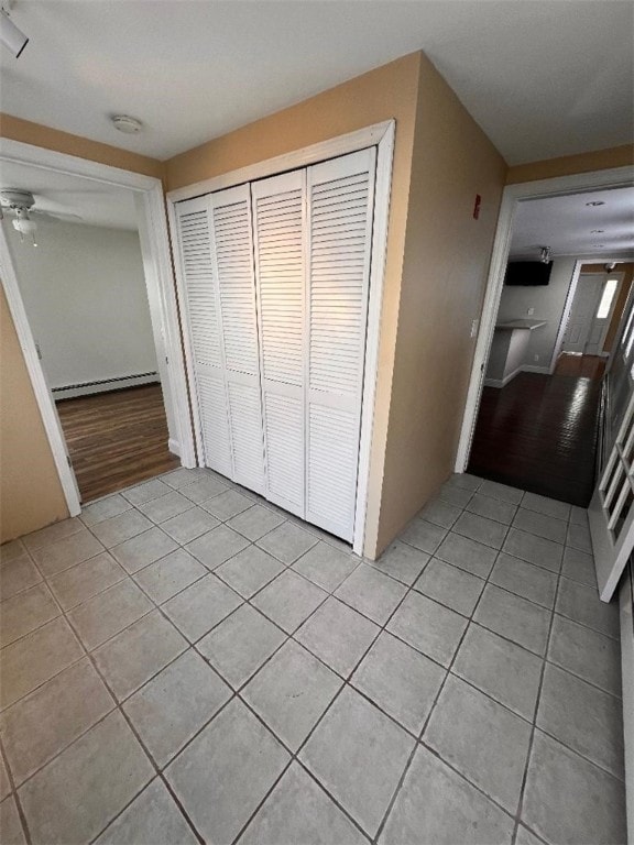 unfurnished bedroom with baseboard heating, a closet, and light tile patterned flooring