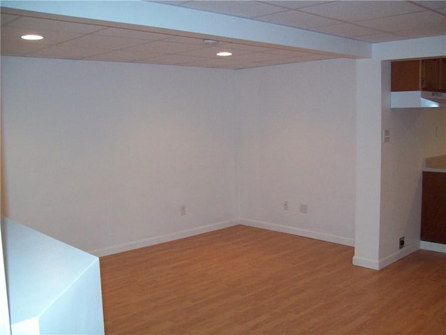 basement featuring a paneled ceiling and hardwood / wood-style flooring