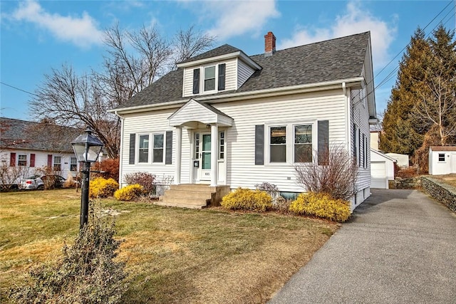 view of front of house featuring a front yard, a garage, and an outdoor structure