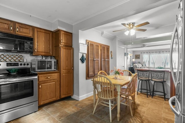 kitchen with brown cabinetry, crown molding, baseboards, a ceiling fan, and stainless steel appliances