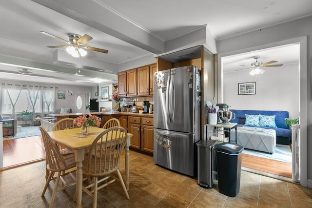 kitchen with brown cabinetry, freestanding refrigerator, a ceiling fan, and crown molding
