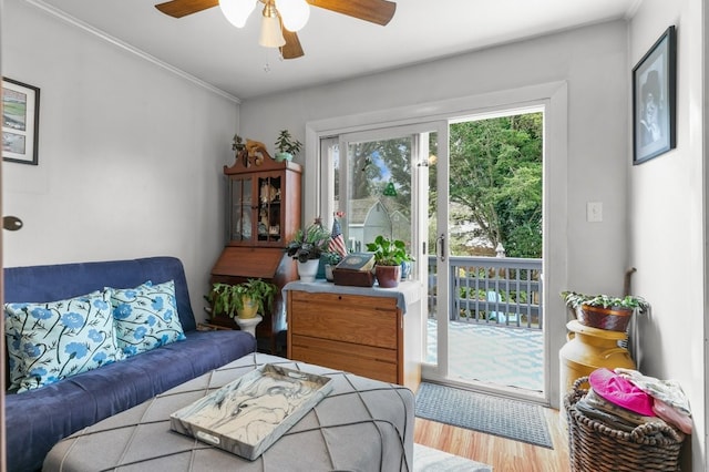 living area with ornamental molding, ceiling fan, and wood finished floors
