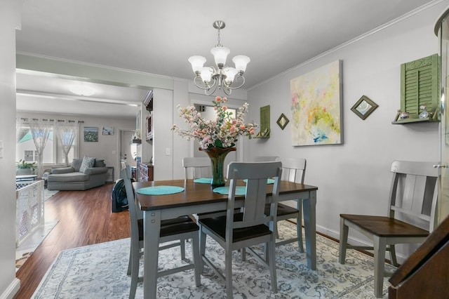 dining area featuring hardwood / wood-style flooring, ornamental molding, and a notable chandelier