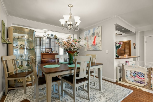 dining space featuring crown molding, wood-type flooring, and a notable chandelier