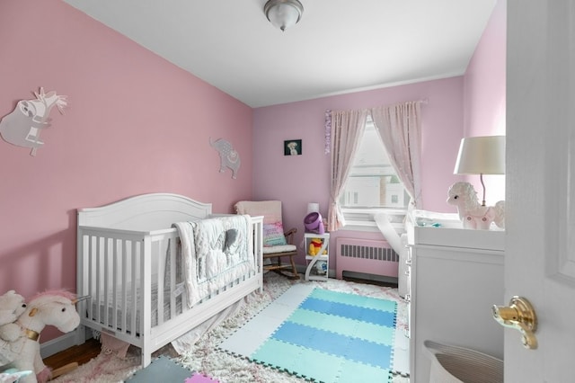 bedroom featuring radiator heating unit and a nursery area