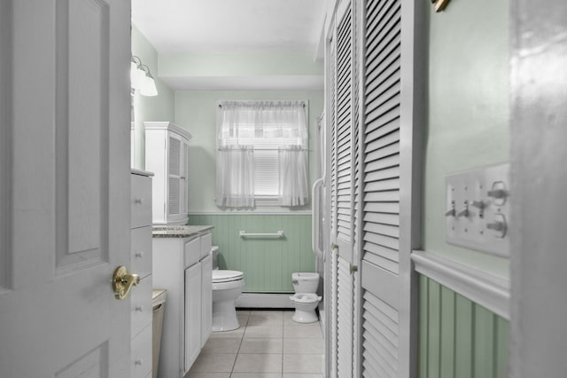 bathroom with vanity, wainscoting, toilet, tile patterned floors, and a baseboard radiator