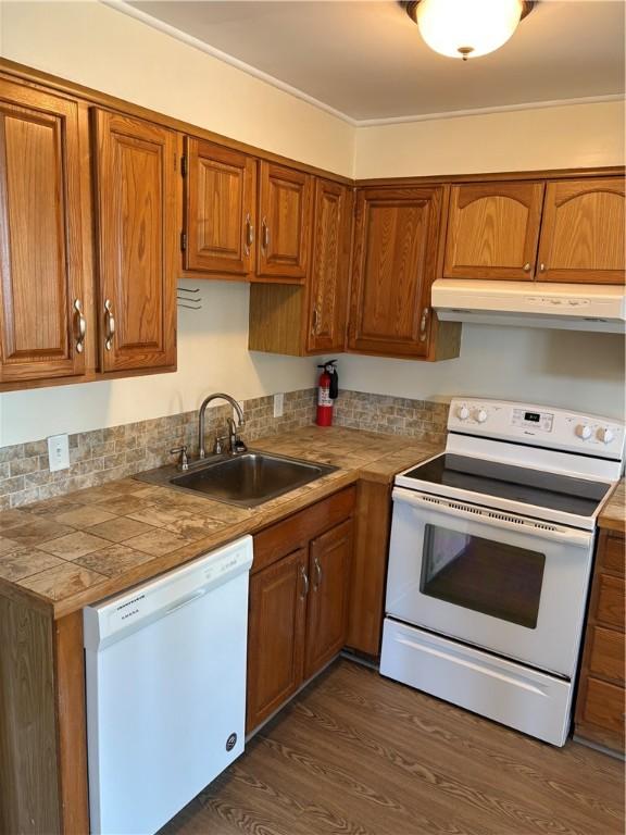kitchen with a sink, extractor fan, brown cabinets, and white appliances
