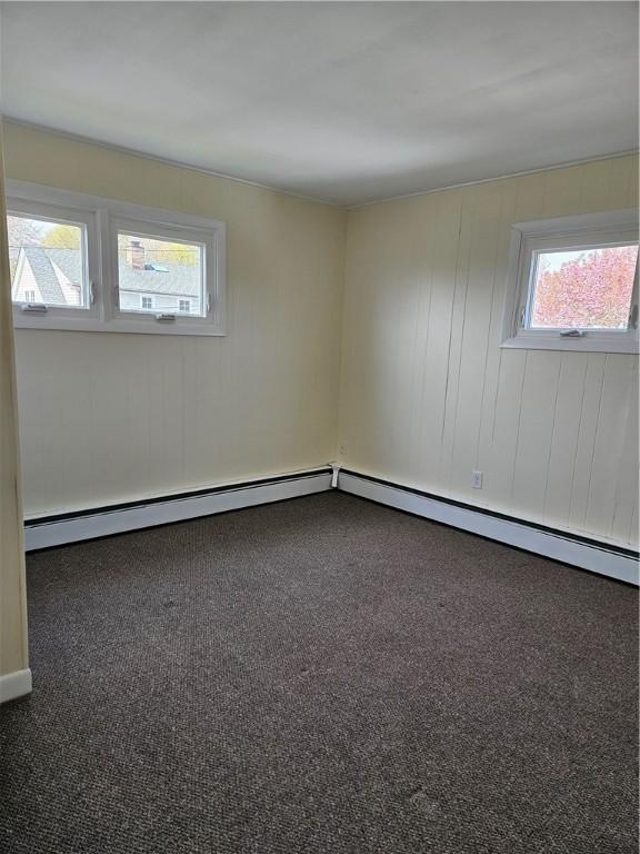 carpeted empty room with plenty of natural light and a baseboard heating unit