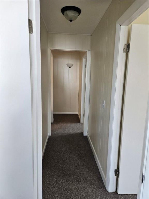 hall with dark carpet and baseboards