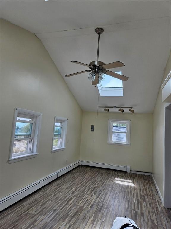 spare room featuring ceiling fan, a skylight, wood finished floors, high vaulted ceiling, and a baseboard heating unit