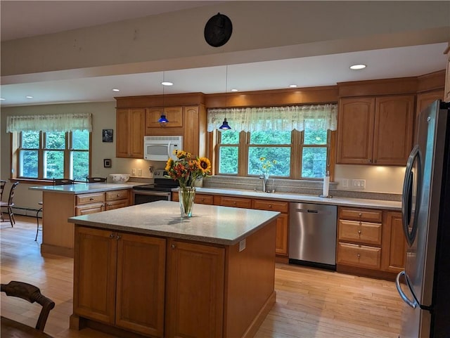 kitchen with light wood-type flooring, a kitchen island, plenty of natural light, and appliances with stainless steel finishes