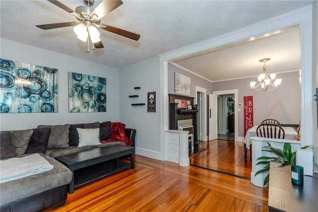 living room featuring ornamental molding, ceiling fan with notable chandelier, and hardwood / wood-style floors