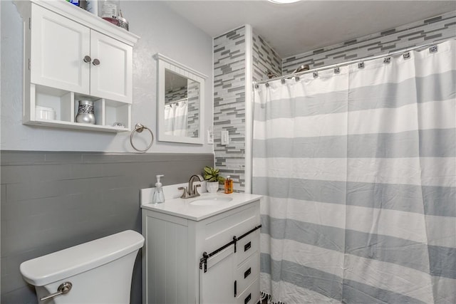 bathroom with toilet, tile walls, and vanity