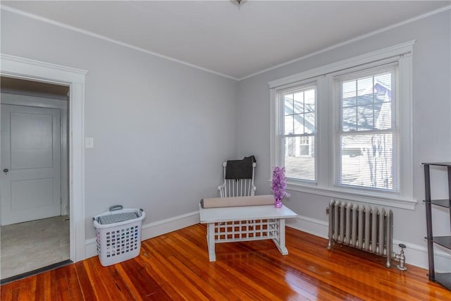 sitting room with hardwood / wood-style floors, radiator heating unit, and crown molding