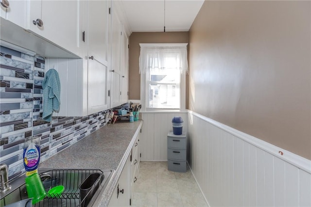 kitchen with white cabinets, decorative backsplash, sink, and light tile patterned floors