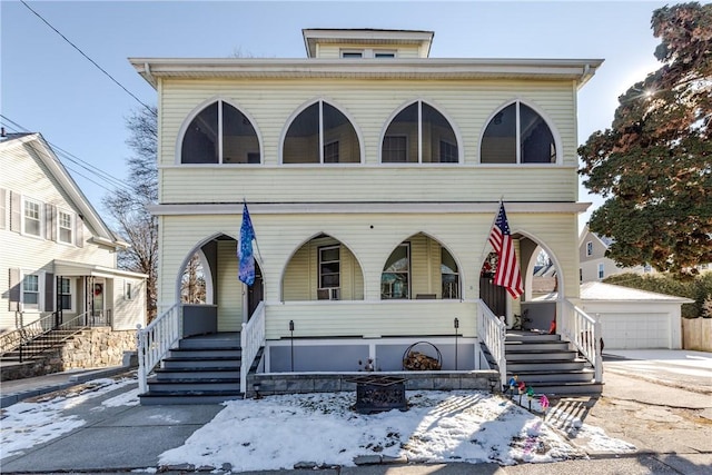 view of front of property featuring a porch, a garage, and an outbuilding