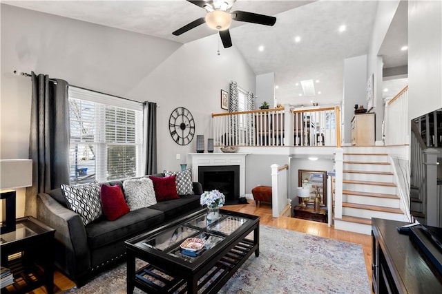 living room with ceiling fan, lofted ceiling, and light hardwood / wood-style flooring