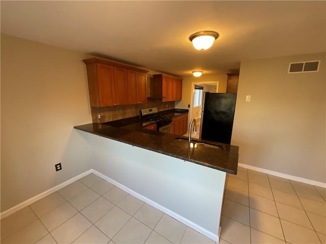 kitchen featuring kitchen peninsula, appliances with stainless steel finishes, sink, and dark stone countertops