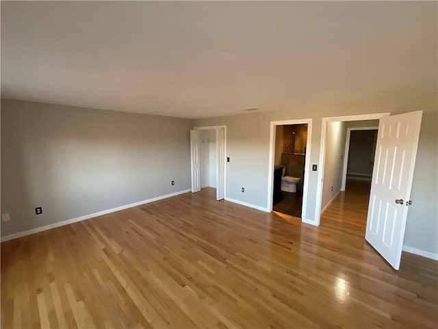 unfurnished bedroom with wood-type flooring and ensuite bath