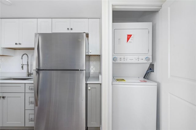 laundry room with stacked washer and dryer and sink