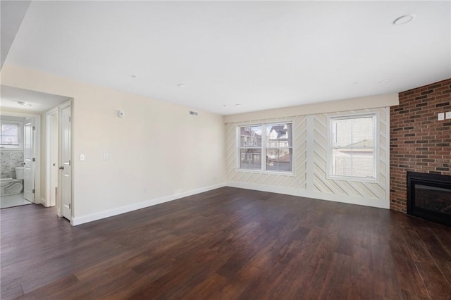 unfurnished living room with a fireplace and dark wood-type flooring