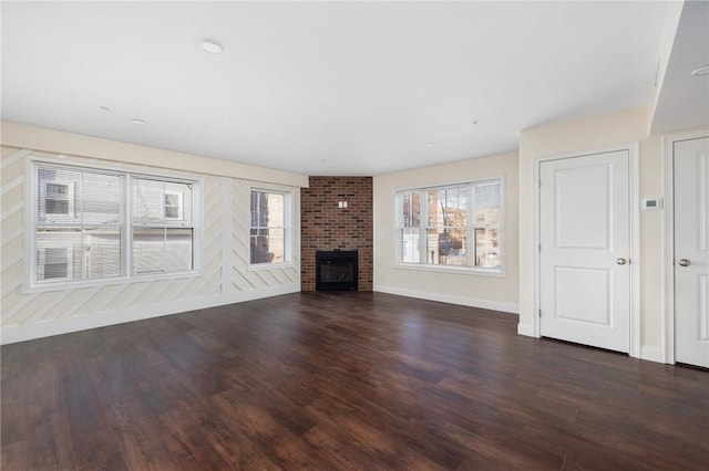 unfurnished living room with dark wood-type flooring and a brick fireplace