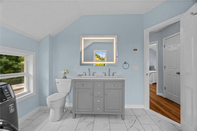 bathroom featuring toilet, vanity, lofted ceiling, and washer / clothes dryer