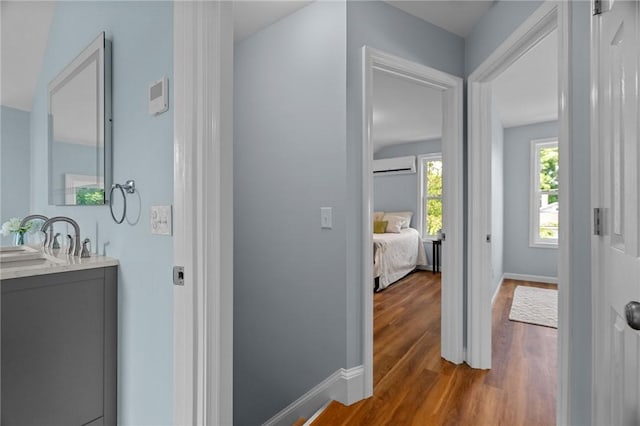 corridor with hardwood / wood-style flooring, sink, and a wall unit AC