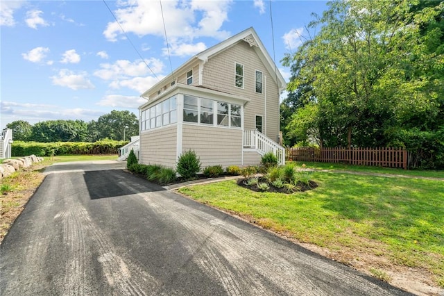 view of property exterior featuring a lawn and a sunroom