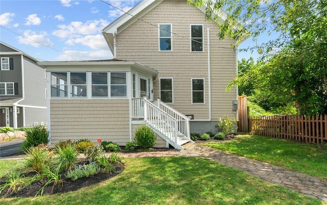 rear view of property featuring a yard and a sunroom