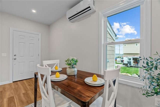 dining area featuring a wall unit AC and light hardwood / wood-style floors