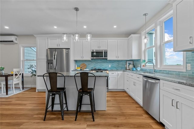 kitchen featuring pendant lighting, white cabinetry, stainless steel appliances, and a wall mounted AC