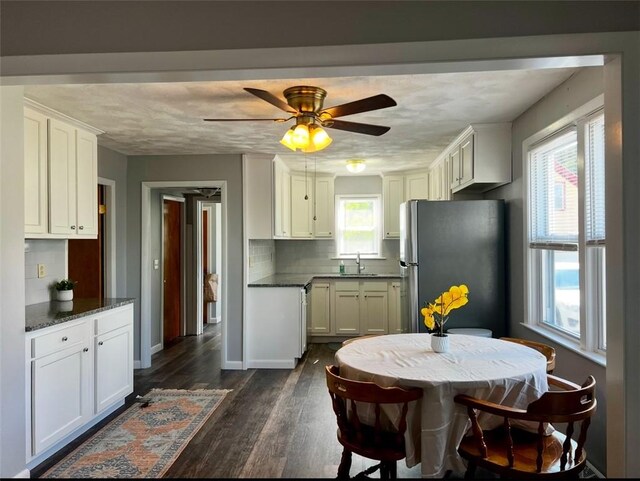 kitchen featuring white cabinetry, ceiling fan, dark wood-type flooring, stainless steel refrigerator, and sink