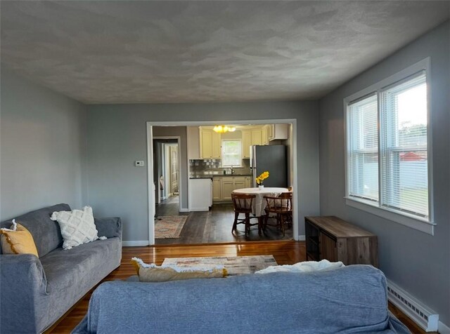 living room featuring a baseboard heating unit, dark hardwood / wood-style flooring, and sink