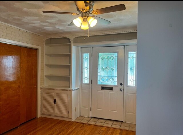 entrance foyer with a wealth of natural light, brick wall, light hardwood / wood-style floors, and ceiling fan