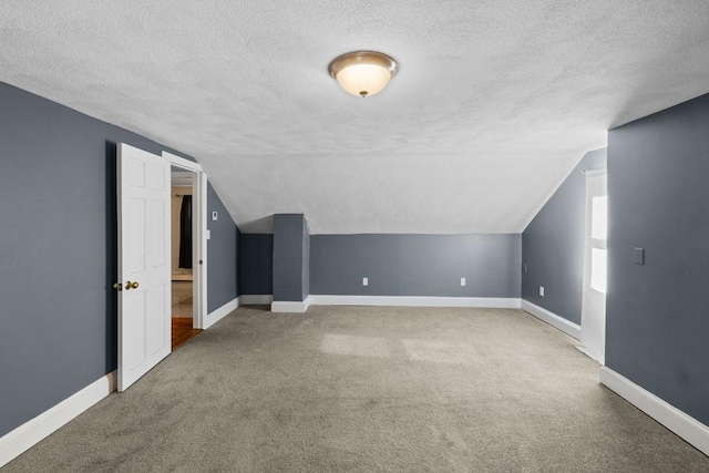 bonus room featuring lofted ceiling, carpet floors, and a textured ceiling