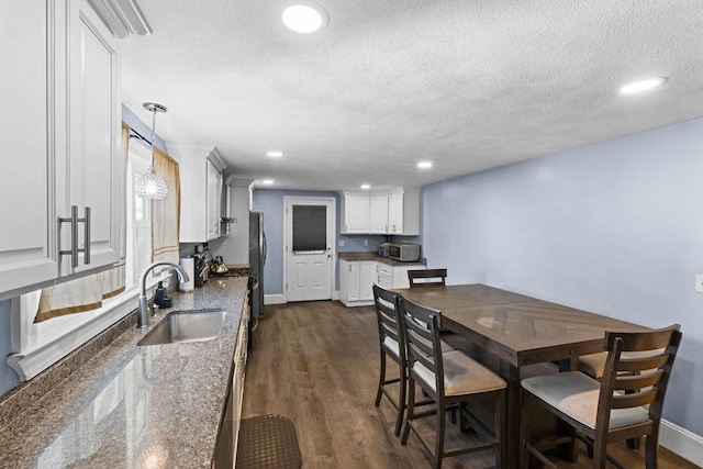 dining area with dark wood-type flooring, sink, and a textured ceiling