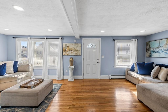 living room featuring beamed ceiling, a baseboard radiator, hardwood / wood-style flooring, and a textured ceiling