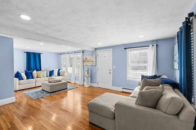 living room featuring a baseboard heating unit, light hardwood / wood-style floors, and a textured ceiling